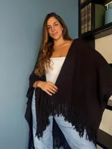 Ruana tejida a mano en punto arroz con lana merino, presenta un diseño envolvente con flecos en los extremos.