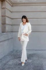 Pantalón de lino color beige claro, de tiro alto y pierna acampanada, con pinzas delanteras.