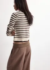Cardigan de punto fino con diseño a rayas horizontales en color crudo y marrón, cuello redondo, manga larga y cierre frontal con botones.