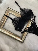Conjunto de lencería compuesto por un top bralette de encaje con breteles regulables y una tanga colaless regulable con detalles de tiras.