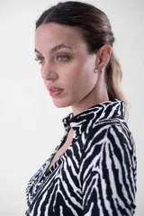 Vestido midi de corte ajustado, con estampado animal print tipo cebra en blanco y negro, cuello camisero, escote en V y cierre frontal con botones dorados.