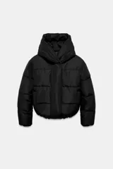 Campera puffer acolchada de color negro, con cuello envolvente, capucha integrada, manga larga, bolsillos laterales ocultos y bajo con elástico. Cierre frontal con botones a presión ocultos por solapa.