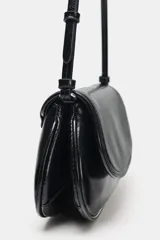Bolso de hombro tipo baguette con acabado brillante, solapa frontal con cierre de botón imantado y asa ajustable.