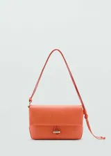 Bolso de hombro pequeño en color naranja, con diseño rectangular y solapa frontal. Presenta un cierre con botón joya metálico y una correa ajustable con nudos laterales.