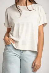 Remera oversize color crudo con sutiles rayas horizontales plateadas, mangas cortas caídas y cuello redondo.