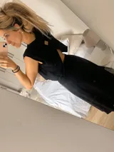 Conjunto de dos piezas compuesto por un top corto sin mangas y una pollera larga con tajo lateral. El top presenta un diseño minimalista y la pollera es ajustable en la cintura.