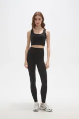 Top deportivo de bretel ancho, color negro, con cuello redondo profundo y diseño ajustado al cuerpo.
