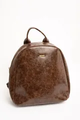 Mochila de cuero sintético marrón con efecto craquelado, asa superior y placa metálica frontal con el logo de la marca.