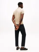 Chomba de mangas cortas color beige, corte slim, con cuello polo y cartera de dos botones. Logo de Tommy Hilfiger bordado en el pecho.