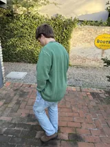 Buzo verde con cuello redondo y logo pequeño bordado en el pecho.