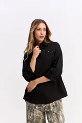 Camisa de algodón color blanco, de corte relajado y estilo western. Presenta detalle de tachas metálicas en la parte superior delantera y mangas largas con puños.