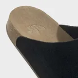 Zuecos Adidas modelo Adimule, color negro, con empeine de ante y suela de corcho con base de goma. Presenta el logo de la marca sutilmente grabado en el empeine.
