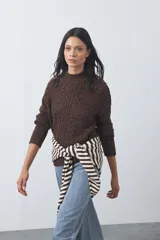 Polera de tejido de punto color marrón, con cuello alto y diseño de textura con relieves y trenzas. Posee mangas largas con puños acanalados.