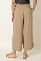 Pantalón ancho color beige, con cintura elastizada, bolsillos laterales y detalle de botones decorativos.