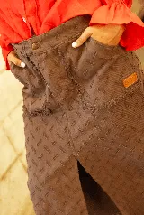 Pollera midi de jean color chocolate, con diseño de textura grabada, bolsillos frontales y tajo central delantero con ruedo desflecado.