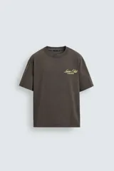 Camiseta de corte relajado con cuello redondo y manga corta. Presenta un efecto lavado y estampados a contraste en el frente y la espalda.