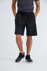 Short deportivo negro con cintura elástica ajustable con cordón, bolsillos laterales con cierre y detalles en verde flúor.