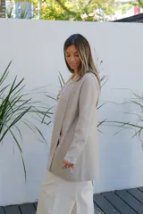 Saco tipo cárdigan abierto de corte recto y largo medio, color visón, con mangas largas y bolsillos frontales aplicados.