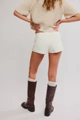 Short de denim rígido blanco, de tiro medio y calce entallado, con cierre de botones, cinco bolsillos y ruedo con dobladillo fijo.