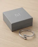 Esclava rígida de acero con diseño de serpiente, decorada con esmalte blanco y detalles en verde en la cabeza.