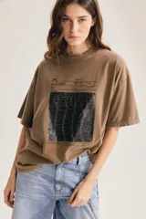 Remera marrón oversize con cuello redondo, mangas cortas y estampa gráfica frontal de diseño técnico con textura.
