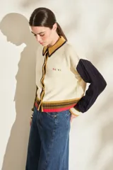 Cardigan de punto con diseño tricolor, de corte relajado, manga larga de tejido trenzado en contraste de color, cuello solapa tipo polo y cierre frontal de botones.