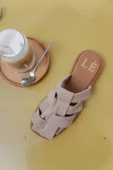Sandalias de cuero con diseño de tiras entrelazadas, estilo jaula, con suela plana y cierre de hebilla lateral.