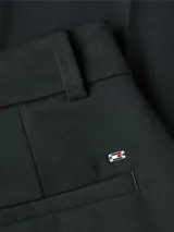 Pantalón negro de vestir, de corte acampanado, con raya marcada en la parte delantera y trasera, bolsillos de ojal y logo esmaltado de Tommy Hilfiger encima del bolsillo trasero.