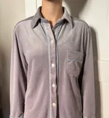 Pijama de dos piezas color rosa pálido, confeccionado en terciopelo. La camisa es de manga larga con botones frontales y bolsillo en el pecho. El pantalón es de corte recto con cintura elástica.