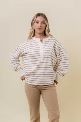 Buzo liviano de manga larga con diseño de rayas horizontales en color beige y blanco. Presenta un cuello redondo con cartera frontal de botones tipo henley, hombros caídos y calce holgado con puños acanalados.