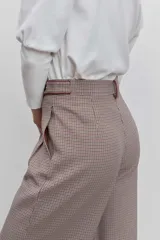 Pantalon de vestir de corte sastrero y pierna ancha, con estampado de cuadros tipo príncipe de gales en tonos tierra. Presenta cintura alta con trabillas, cierre frontal con botones y bolsillos laterales con detalle de ribete.