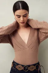 Sweater de punto color marrón claro, con escote en V pronunciado y mangas largas. Presenta un trabajo de calado con diseño de espiga en la parte superior del busto y mangas, y un tejido más ajustado y liso en la zona del torso.