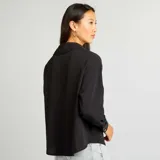 Camisa negra de corte holgado con cuello clásico y mangas largas con puños abotonados.