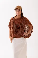 Buzo tejido a mano en lana merino color óxido, con diseño de trama calada, corte amplio y caída relajada.