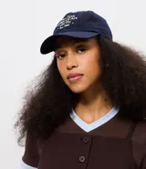 Gorra de sarga color azul marino con ala curva y bordado frontal con texto New York. Cuenta con regulador en la parte posterior para un ajuste personalizado.