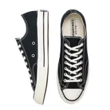 Championes de lona negra con puntera de goma, suela de plataforma de goma en color crema con detalles en negro y cordones blancos.