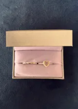 Set de dos anillos de plata 925 con acabado brillante. El primer anillo presenta un diseño entrelazado con pequeñas incrustaciones de zirconias, mientras que el segundo anillo destaca por un dije central en forma de corazón con una piedra amarilla y borde de zirconias.