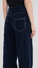 Pantalón de pana de algodón con tiro medio y corte de pierna ancha. Presenta dos bolsillos delanteros, dos bolsillos traseros con pespuntes y cierre frontal con botón y cremallera.