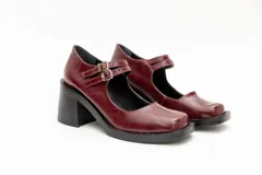 Guillerminas de cuero charol negro con punta cuadrada, taco ancho y correa sobre el empeine con doble hebilla dorada.