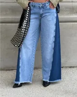 Pantalon de jean de corte wide leg con diseño bicolor, combinando paneles de denim claro en el centro y denim oscuro en los laterales. Presenta ruedo deshilachado y cierre frontal con botón.