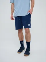 Bermuda deportiva Umbro color azul marino, con cordón ajustable en la cintura, bolsillos laterales, tiras blancas en los laterales y logo de la marca bordado en la pierna izquierda.