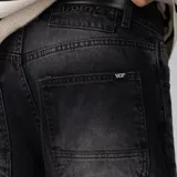 Bermuda de jean baggy color negro con lavado gastado, de corte ancho y largo hasta debajo de la rodilla, con diseño de cinco bolsillos y detalles de recortes en los bolsillos traseros.