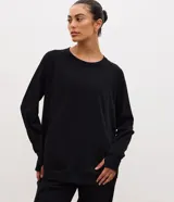 Buzo cerrado de corte oversized, confeccionado en algodón y poliéster. Presenta cuello redondo, mangas largas con puños acanalados y bolsillo delantero funcional. Su diseño incluye detalles de encaje en los laterales y ruedo acanalado.