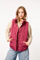 Chaleco puffer color borgoña con diseño capitoneado, cierre frontal con cremallera y botones a presión, y dos bolsillos laterales.