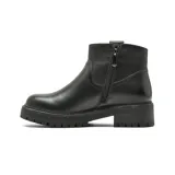 Bota corta de cuero negro con suela track dentada y taco bajo. Presenta un diseño minimalista con costuras reforzadas y un detalle metálico en la parte superior del lateral.