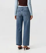 Pantalón de jean de corte recto y tiro bajo, color azul medio con efecto desgastado. Presenta bolsillos delanteros y traseros, y cierre frontal con botón y cremallera.