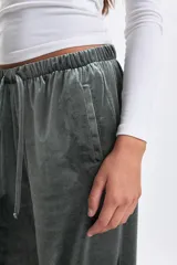 Pantalón de corte ancho confeccionado en tela de plush con acabado satinado. Presenta cintura elástica con cordón de ajuste y bolsillos laterales.