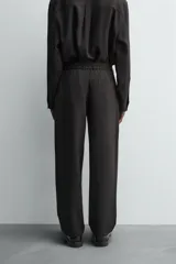 Pantalón de corte relaxed fit, con cintura ajustable, bolsillos delanteros y bolsillo trasero de plastrón. Presenta cierre frontal con cremallera y botón.