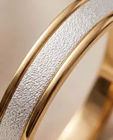 Pulsera esclava rígida de plata 925 y lámina de oro 18k, con banda central texturizada en tono blanco con acabado brillante.