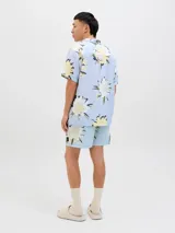 Short de baño de tiro medio con estampado floral en tonos claros sobre fondo celeste. Cuenta con cintura elástica con cordón ajustable, bolsillos laterales y un bolsillo trasero.